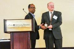 Shree Vikas, director of market intelligence and business analysis at ConocoPhillips, gives Andy Kleit the Senior Fellow Award 